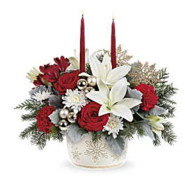 Holiday floral arrangement with red roses, white lilies, and candles in a snowflake vase
