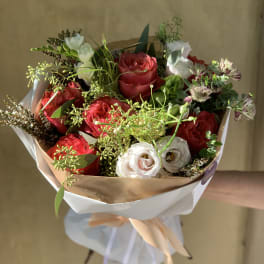 Bouquet of red and white roses with greenery, wrapped in paper and ribbon