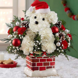 White teddy bear floral arrangement with a Santa hat in a brick-pattern planter