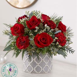 Red roses and carnations in a patterned white vase