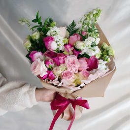 Handheld bouquet of pink and white roses with calla lilies and white blooms