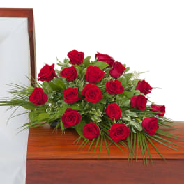 Red rose casket spray arranged on a closed wooden casket