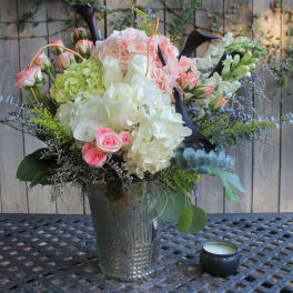 Mixed bouquet of pink, white, and green flowers in a metal vase