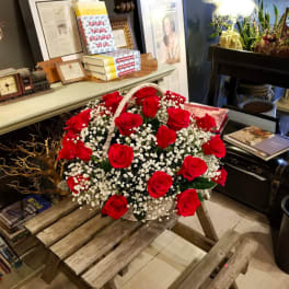 Basket of red roses and baby's breath on a wooden table