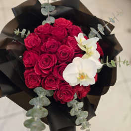 Bouquet of red roses with white orchids and dark wrapping