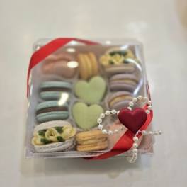 Box of assorted macarons tied with a red ribbon and pearl heart decoration