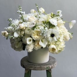 White floral arrangement in a cream vase on a stool