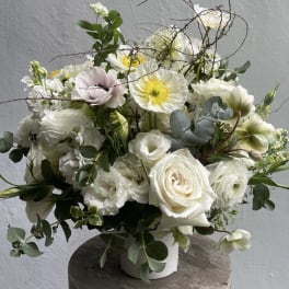 White floral arrangement in a white vase with roses and poppy-like blooms