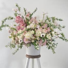 Large pink and white floral arrangement in a white vase