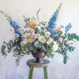 Large floral arrangement in a metal urn with blue and white blooms