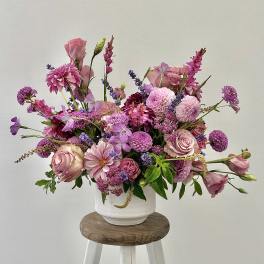 Pink and purple mixed flower arrangement in a white vase
