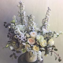 White and blush floral arrangement in a textured vase