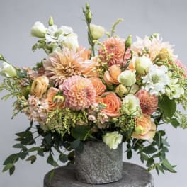 Peach and white mixed flower arrangement in a gray vase