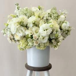 White floral arrangement in a pale blue vase on a stool