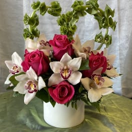 Pink roses and white orchids arranged in a white vase