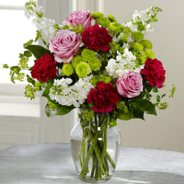 Bouquet of pink roses, red carnations, and white flowers in a glass vase