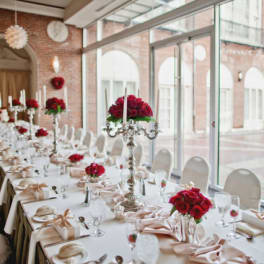 Long banquet table with red rose centerpieces and white candles