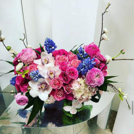 Pink and blue floral arrangement with orchids and roses in a vase