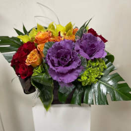 Bouquet of red and orange roses with purple ornamental cabbage in a box