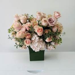 Pink roses and pale hydrangeas arranged in a green vase