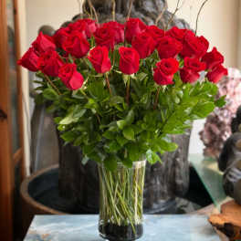 Red roses arranged in a tall glass vase