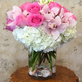 Pink roses and pale orchids in a glass vase with white hydrangeas