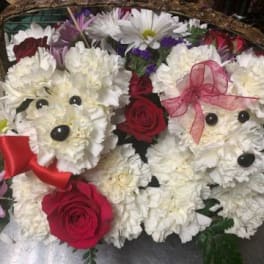 Two teddy bear floral arrangements with red roses and white flowers