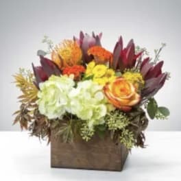 Mixed floral arrangement in a wooden box with orange and yellow blooms