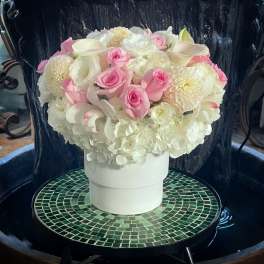 Pink and white floral arrangement in a white hatbox