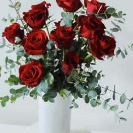 Red roses in a white vase with eucalyptus