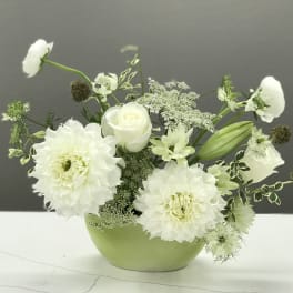 White flowers arranged in a light green bowl vase
