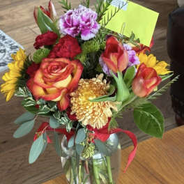 Mixed bouquet of roses, tulips, carnations, and chrysanthemums in a glass vase