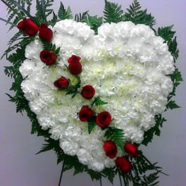 Heart-shaped white floral spray with red roses on a stand