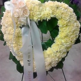 Heart-shaped white floral wreath with ribbon and roses