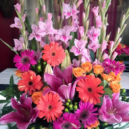 Tall mixed bouquet with pink gladiolus, gerbera daisies, and orange roses