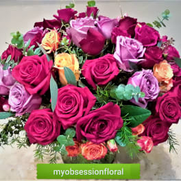 Bouquet of pink, purple, and orange roses in a glass vase