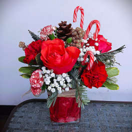 Red roses and carnations in a red vase with candy canes and pinecones