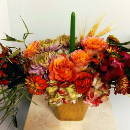 Autumn floral arrangement with orange and red blooms in a gold vase