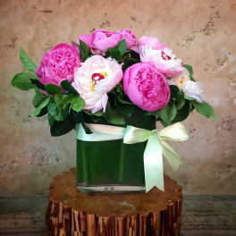 Pink peonies in a glass vase with a white ribbon