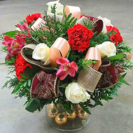 Bouquet of red carnations, white roses, and pink alstroemeria in a glass vase