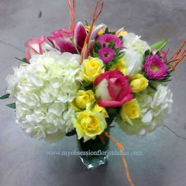 Bouquet of white hydrangeas, pink roses, and yellow roses in a glass vase