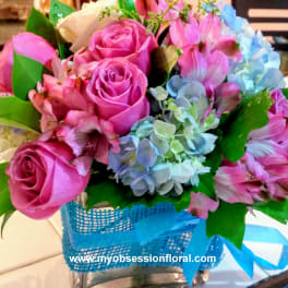 Pink roses and blue hydrangeas in a blue basket with ribbon