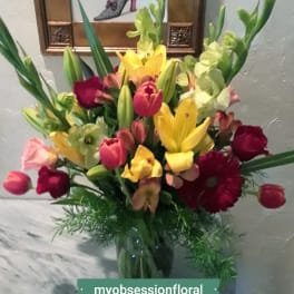 Mixed bouquet of lilies, tulips, and roses in a glass vase