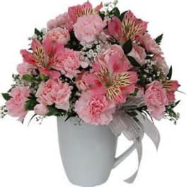 Pink mixed flower arrangement in a white mug with a ribbon