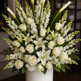 White roses and calla lilies arranged in a white vase