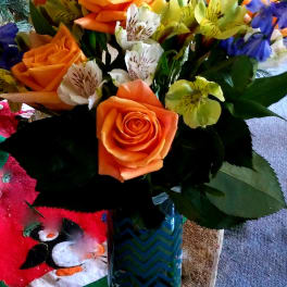 Orange roses and mixed lilies in a glass vase