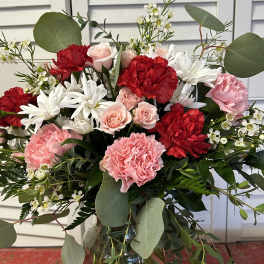 Bouquet of red and pink carnations with white daisies in a glass vase
