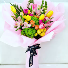 Mixed bouquet of tulips, roses, and alstroemeria wrapped in pink paper