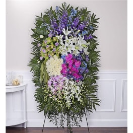Standing funeral spray with white lilies, orchids, and purple flowers