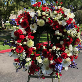Large circular wreath of red, white, and purple flowers on an easel